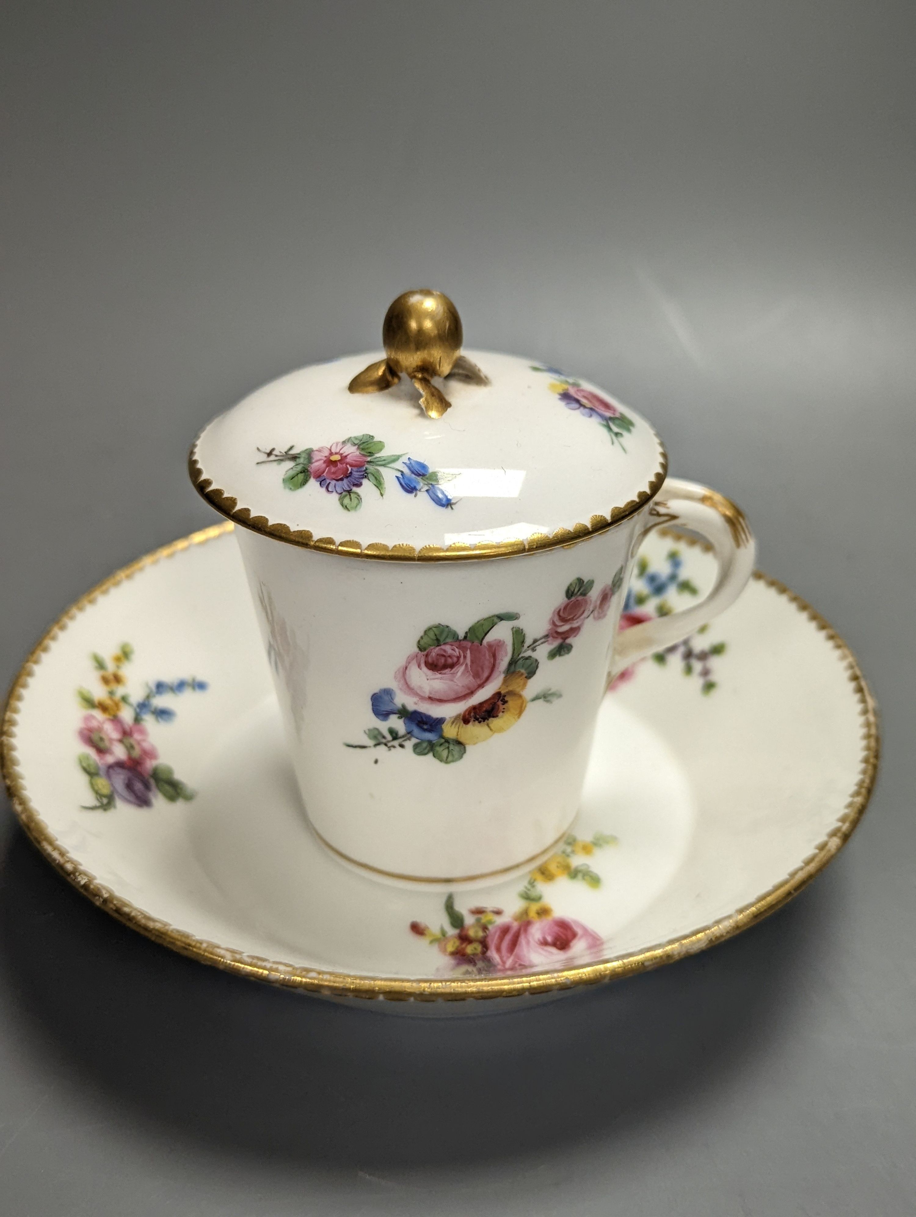 A Sevres tapering cup with entwined handle and cover and stand painted with flowers, date code for 1780, painters mark for Le Bel jnr., square incised marks, height 10.5cm